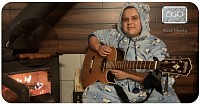 Bassetronaute, rose-Andrée monty avec sa guitare près d’un feu avec ses saussisse et une beau sourire